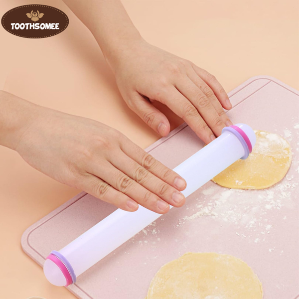 Small plastic fondant rolling pin on a kitchen counter next to rolled fondant