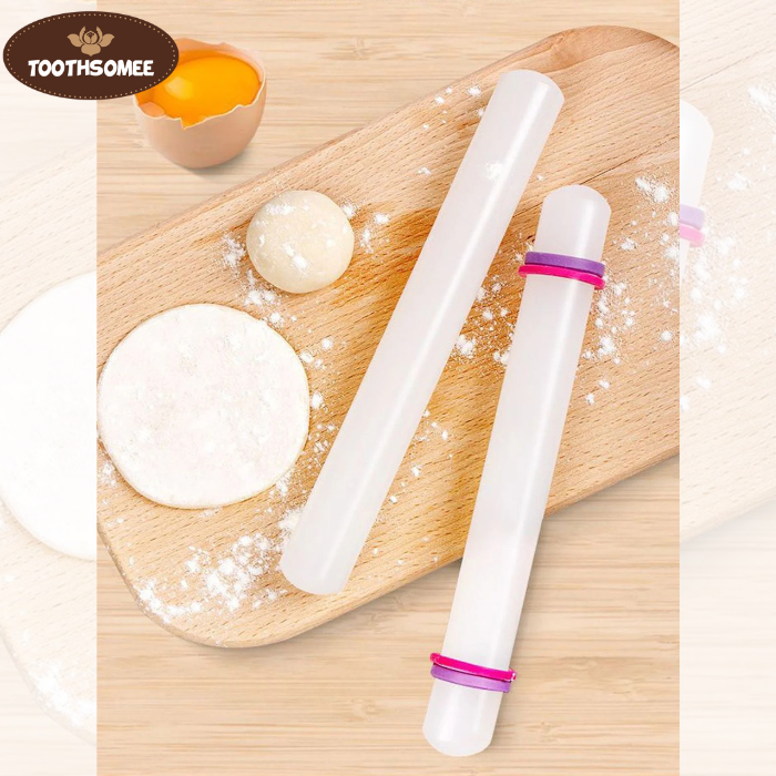 Small plastic fondant rolling pin on a kitchen counter next to rolled fondant